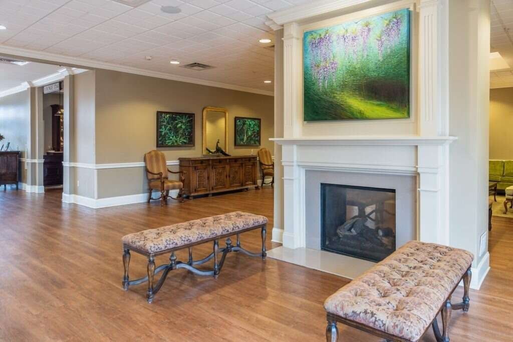 Lobby with fireplace, art, benches, and hardwood floors. A warm, inviting space.