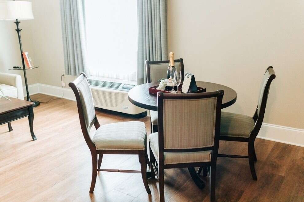 Dining area with round wooden table, four chairs, champagne, and a tray.
