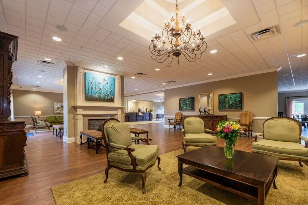 Elegant living room with armchairs, fireplace, chandelier, and artwork.