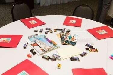 Round white table with red folders, brochures, and small items.